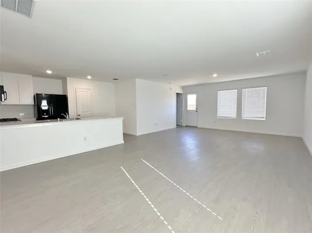 a view of an empty room with kitchen appliances and a window