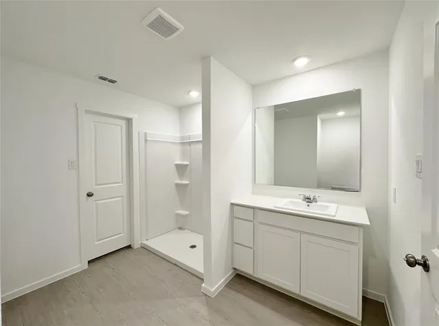 a spacious bathroom with double sink large mirror and shower