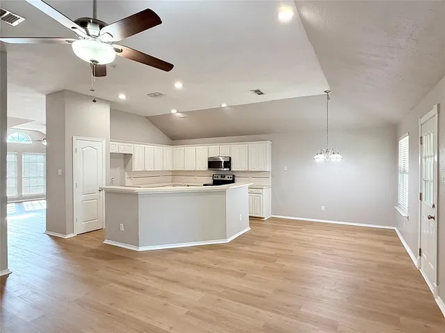 a kitchen with a sink a stove top oven a refrigerator and white cabinets
