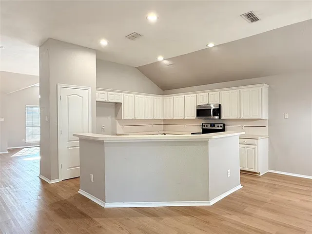 a view of a room with wooden floor and a ceiling fan