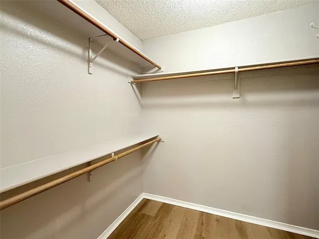 an empty room with wooden floor closet and windows