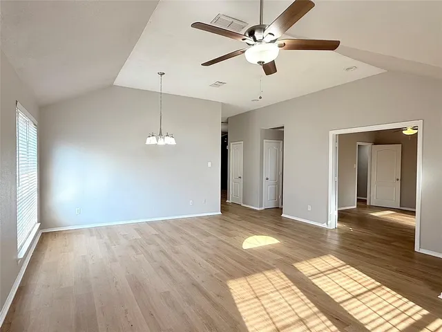 a view of an empty room with window and wooden floor