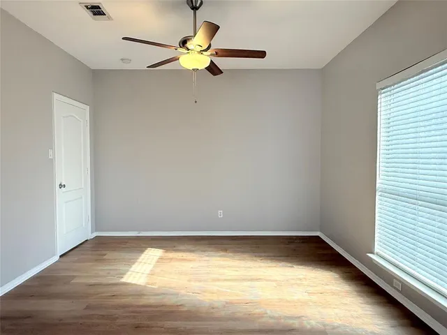 an empty room with a window and a ceiling fan