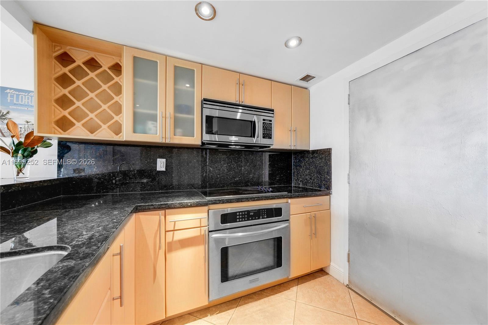 345 Ocean Drive, Unit 703 Miami Beach, FL 33139 - Photo 8 of 15 a kitchen with granite countertop wooden cabinets stainless steel appliances and a counter top space