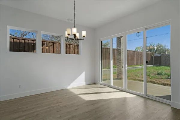 a view of a room with wooden floor chandelier and windows