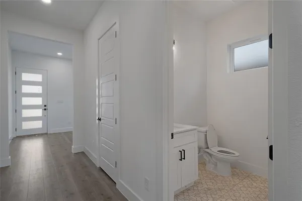 a bathroom with a toilet a sink and wooden floor