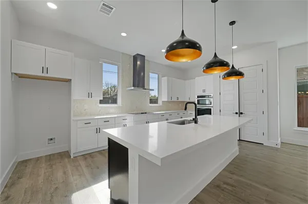 a kitchen with stainless steel appliances granite countertop a sink a stove and a wooden floors