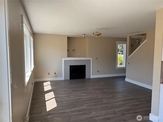 a view of empty room with wooden floor and fireplace