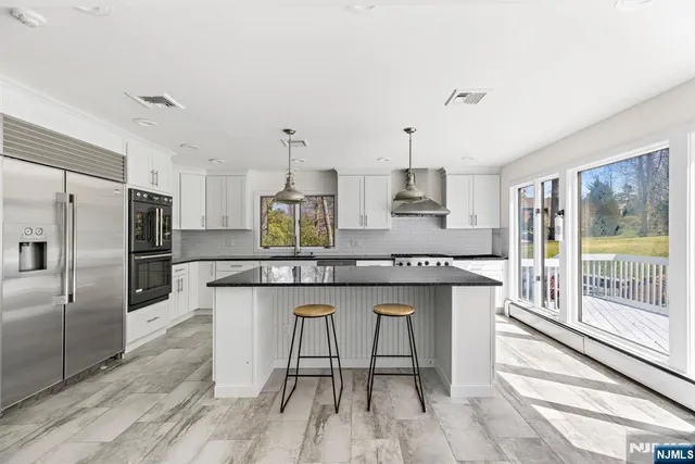 a kitchen with stainless steel appliances granite countertop a table chairs stove refrigerator and cabinets