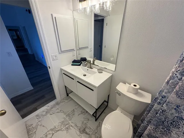 a white toilet sitting next to a white sink and vanity