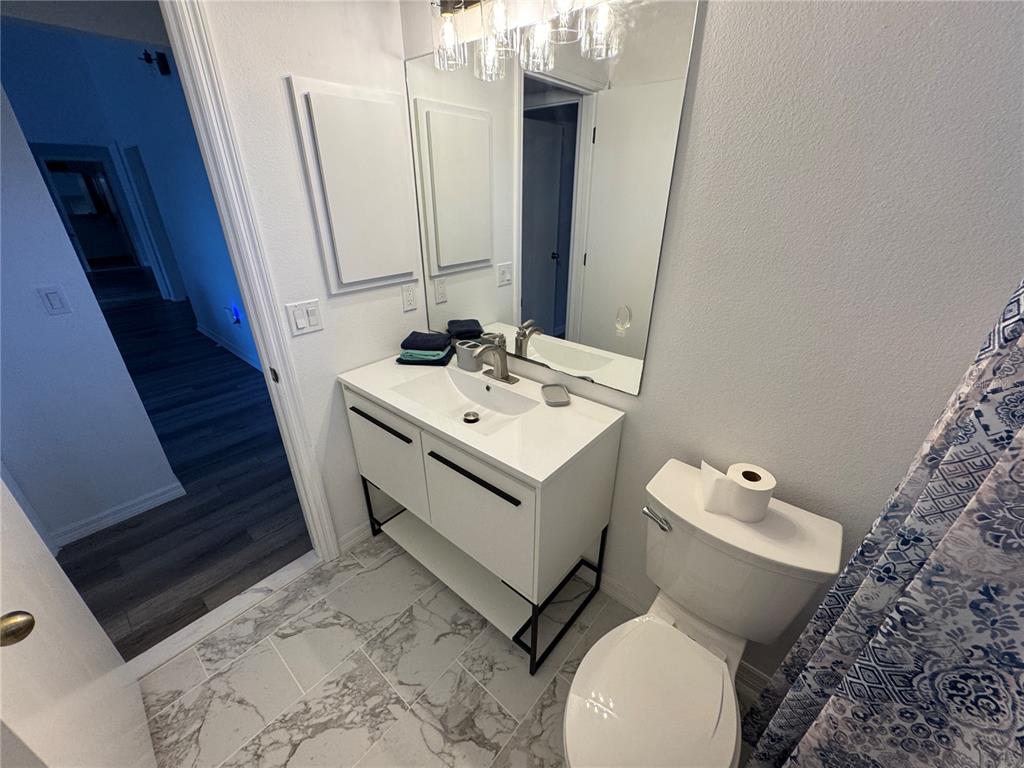 2466 Logsdon Street North Port, FL 34287 - Photo 16 of 18 a white toilet sitting next to a white sink and vanity