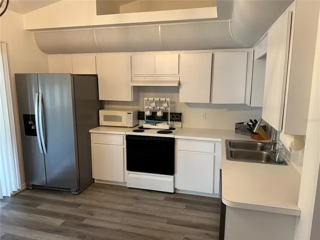 a kitchen with a refrigerator sink and cabinets
