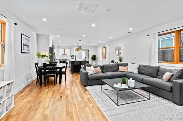 a living room with furniture wooden floor and kitchen view