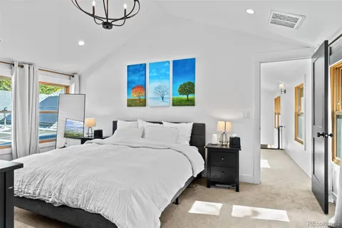 a bedroom with a bed a mirror on dresser and a chandelier