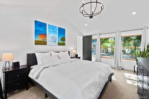 a bedroom with a bed a dresser and a chandelier