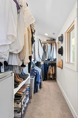 a view of walk in closet with clothes and shoes