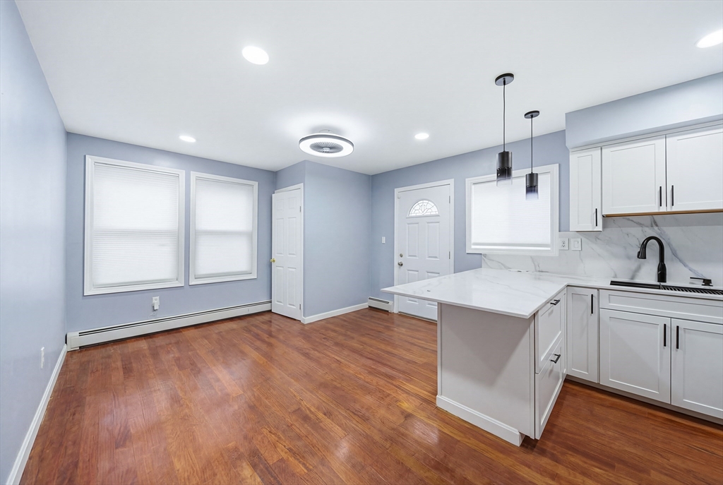 39 Hawthorne Street, Unit 39 Boston, MA 02119 - Photo 13 of 33 a kitchen with granite countertop a stove a sink and white cabinets with wooden floor