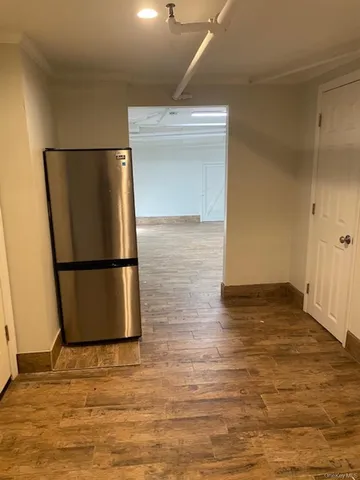 a view of a refrigerator in kitchen and empty room with wooden floor