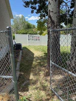 641 East Greystone Way Tooele, UT 84074 - Photo 22 of 30 Grassed side yard featuring mature trees and a chain-link fence
