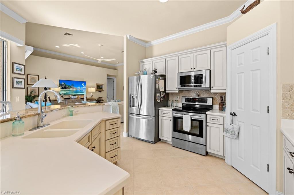 6737 Bent Grass Drive Naples, FL 34113 - Photo 8 of 31 a kitchen with white cabinets and stainless steel appliances