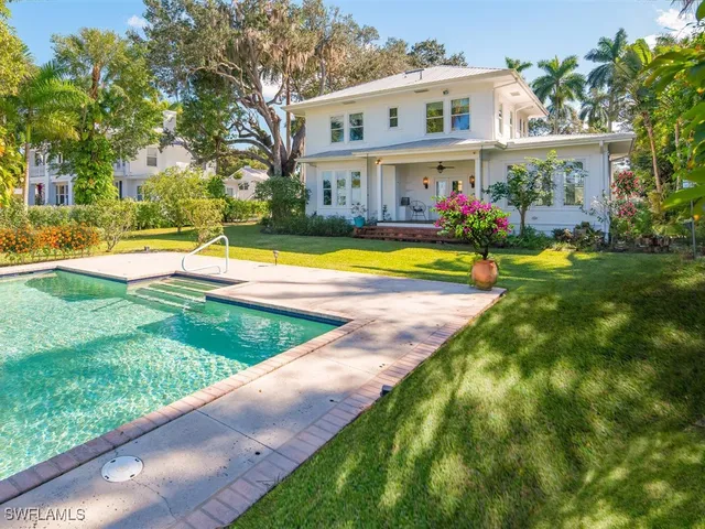 a view of an house with swimming pool lawn chairs and a yard