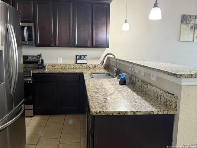 a kitchen with granite countertop a refrigerator and a sink