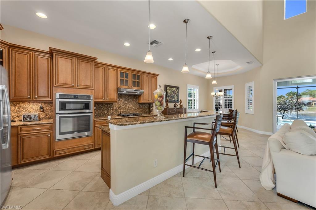 7810 Martino Circle Naples, FL 34112 - Photo 6 of 23 a kitchen with kitchen island granite countertop wooden cabinets and stainless steel appliances