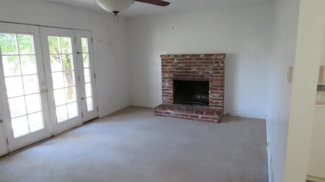 an empty room with windows and fireplace
