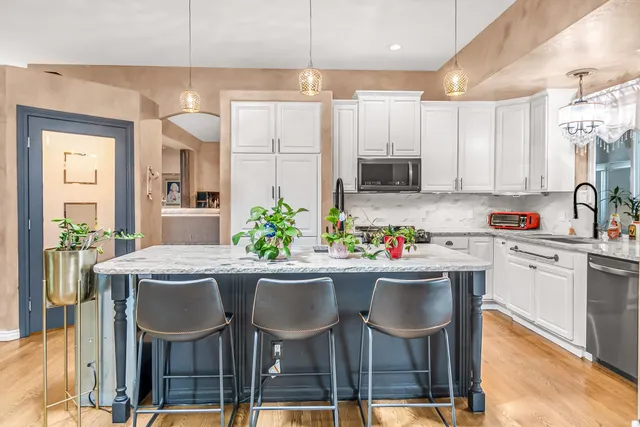 a kitchen with kitchen island granite countertop a dining table chairs and white cabinets