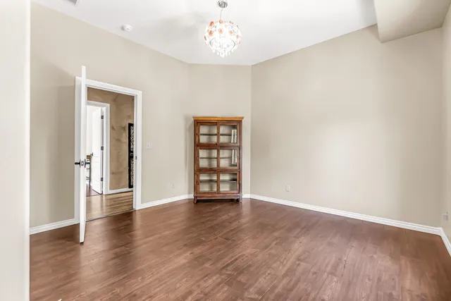 an empty room with wooden floor cabinet and windows