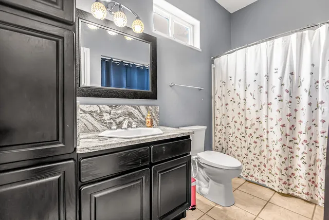a bathroom with a granite countertop sink and a toilet