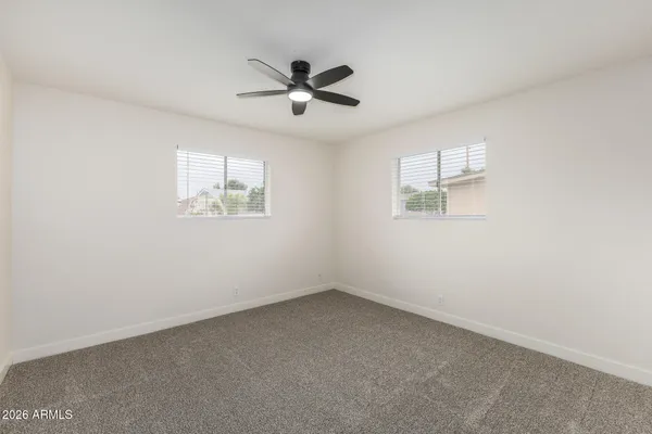 an empty room with windows and fan