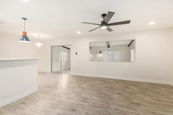 a view of an empty room with wooden floor and a ceiling fan