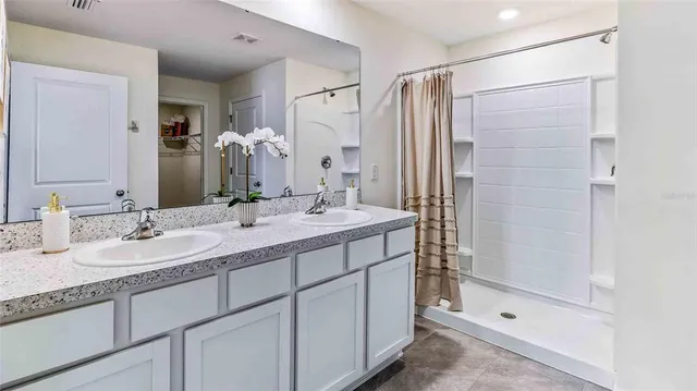 a bathroom with a double vanity sink mirror and shower