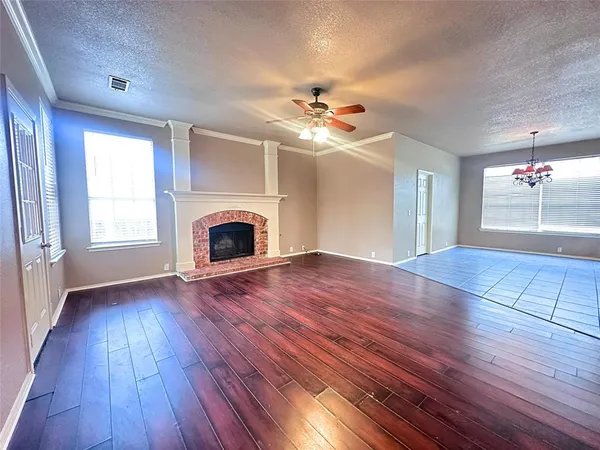 a view of an empty room with wooden floor and a ceiling fan