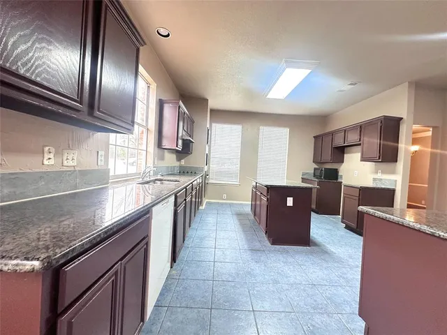 a kitchen with stainless steel appliances granite countertop a stove a sink and a microwave