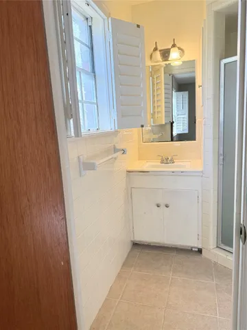 a view of a bathroom with a sink a mirror and a window