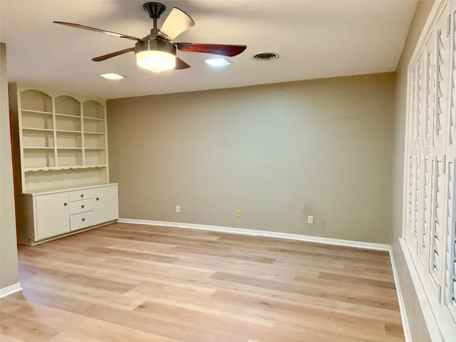 an empty room with a window and chandelier fan