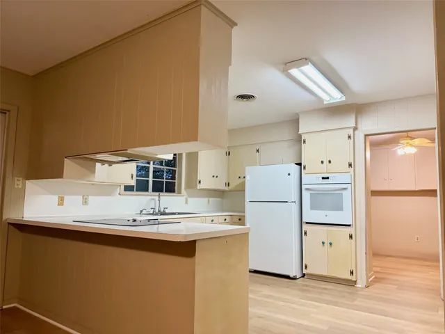 a kitchen with a refrigerator sink stove and wooden floor