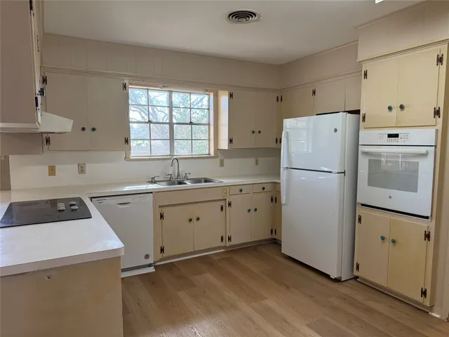 a kitchen with a refrigerator a stove a sink and cabinets