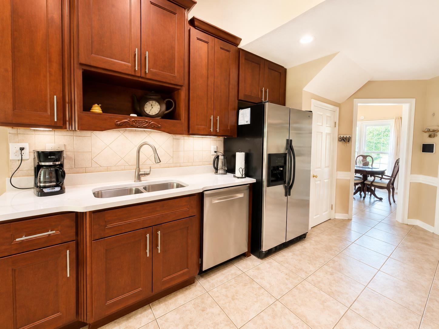 326 South Sanga Road Cordova, TN 38018 - Photo 14 of 32 Functional kitchen featuring cherry wood cabinetry, light-toned countertops, a stainless steel double-basin sink with a pull-down faucet, and a tile backsplash