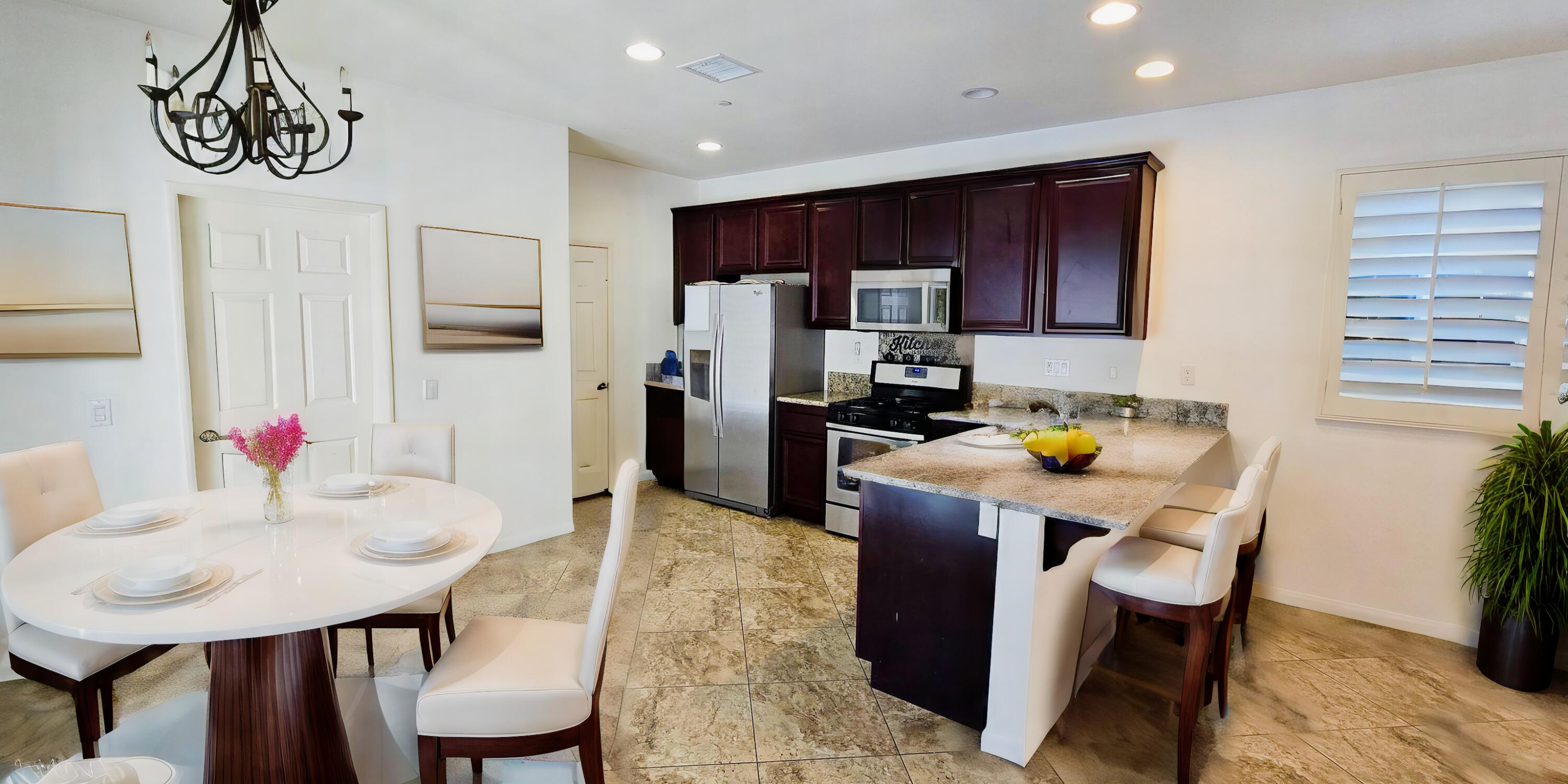 49818 Minelli Street Indio, CA 92201 - Photo 5 of 11 a kitchen with stainless steel appliances kitchen island granite countertop a table chairs and a refrigerator