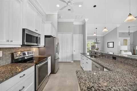 a large kitchen with a stove a sink a microwave a refrigerator and cabinets