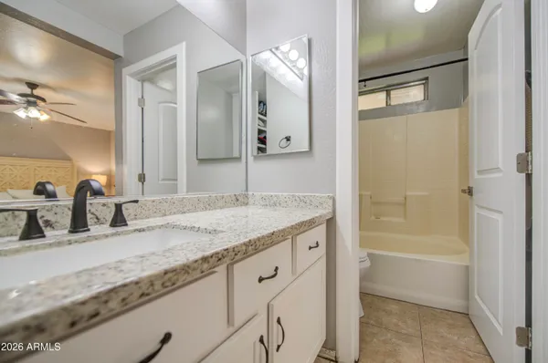 a bathroom with a granite countertop sink mirror and a bath tub