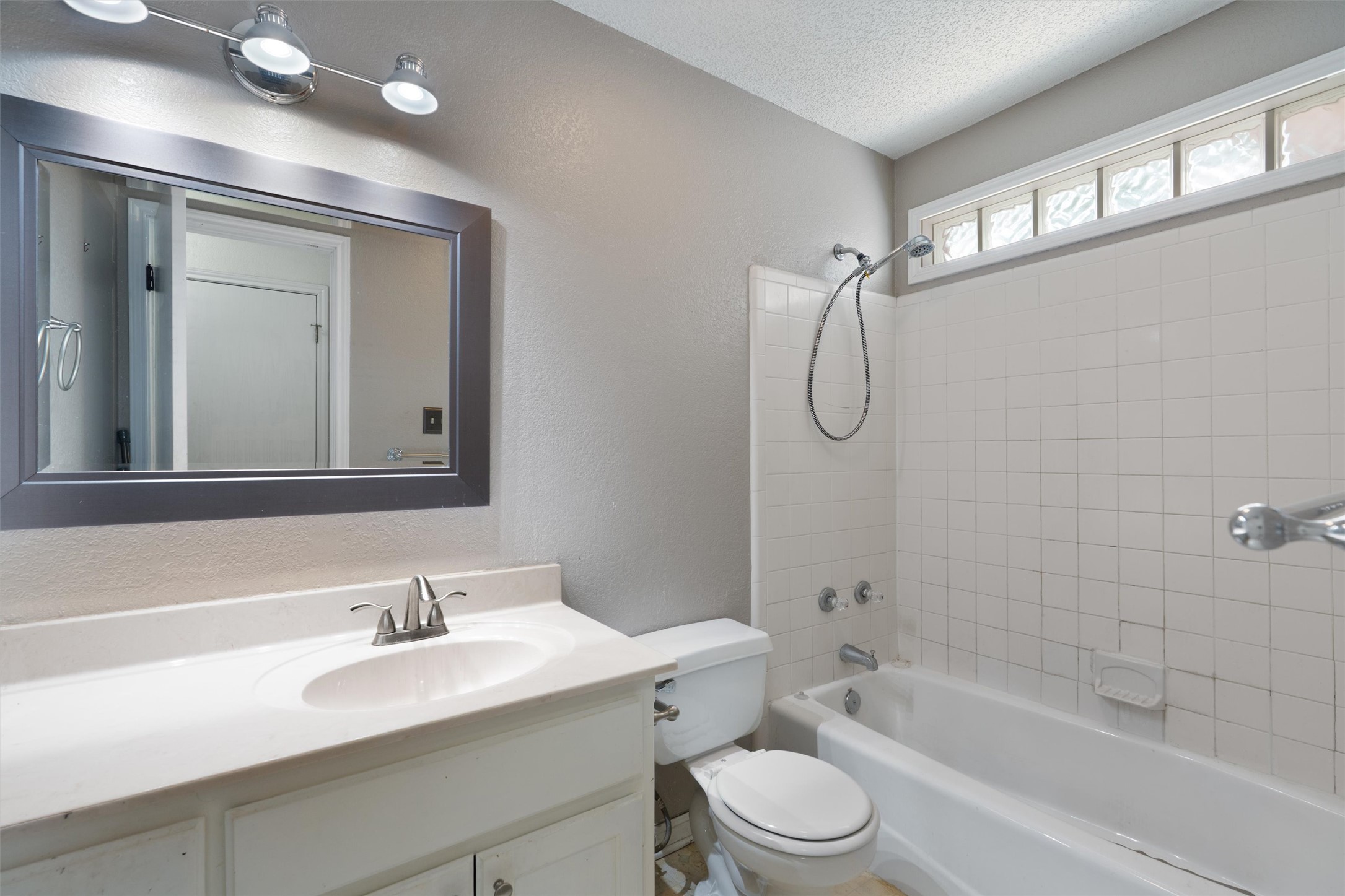 2306 Raintree Path Round Rock, TX 78664 - Photo 20 of 23 Brightly illuminated vanity with a mirror provides functionality for daily routines, alongside a tiled tub and shower combination.