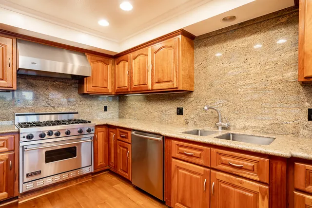 a kitchen with stainless steel appliances granite countertop a sink stove and cabinets