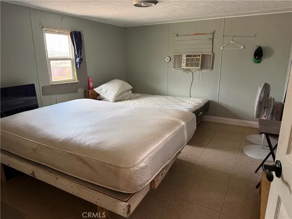 a bedroom with a bed a chair and potted plant on the dresser
