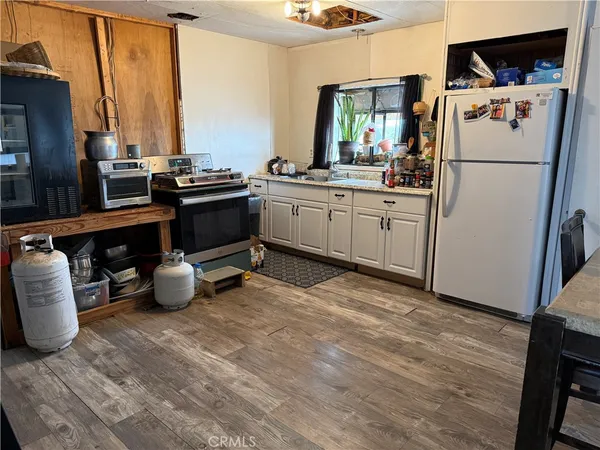 a kitchen with refrigerator a stove and a wooden floor