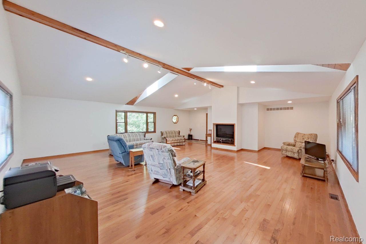 10201 Washburn Road Goodrich, MI 48438 - Photo 15 of 85 Spacious living area featuring light wood-finish flooring, a contemporary fireplace, and high vaulted ceilings with exposed wood beams