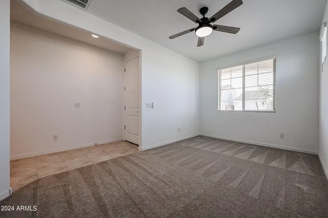 an empty room with ceiling fan and window